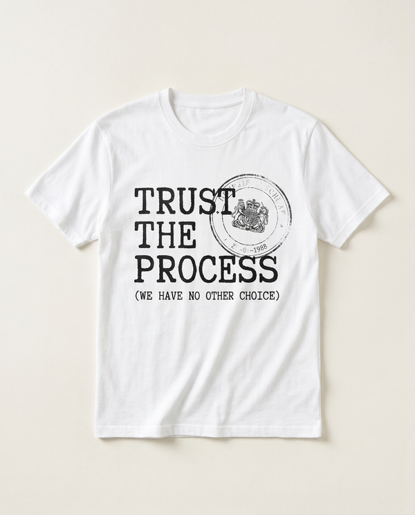 Trust The Process rubber-stamp satire tee, flat-lay on bone background