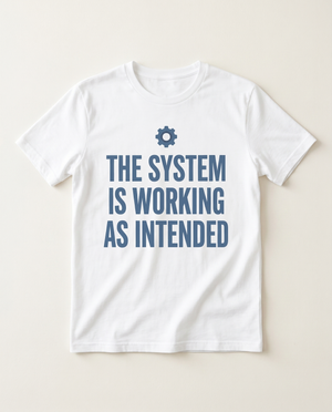 The System Is Working As Intended corporate-poster tee, flat-lay on bone background